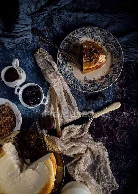 De cima bolo de queijo com delicioso caramelo líquido em composição com ingredientes e utensílio entre tecidos delicados na mesa de mármore azul — Fotografia de Stock
