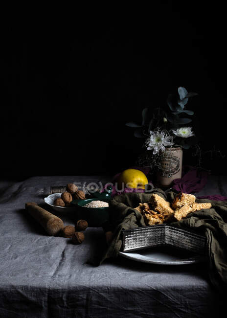 Frische knusprige Kekse im Teller mit Serviette und Muskatnüssen in Schüssel auf dem Tisch mit Tischdecke bedeckt — Stockfoto