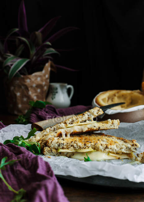 Desde arriba delicioso sándwich tostado en plato colocado en la mesa de madera con queso molde blanco al horno y peras maduras - foto de stock