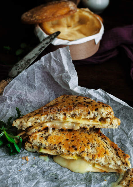 Desde arriba delicioso sándwich tostado en plato colocado en la mesa de madera con queso molde blanco al horno y peras maduras - foto de stock
