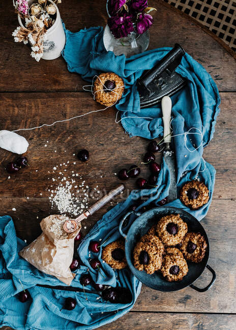 Top view of yummy baked cherry cookies placed on wooden table with piece of cloth and vintage iron — Stock Photo