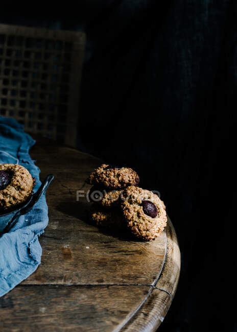 From above of yummy baked cherry cookies placed on wooden table with piece of cloth and vintage iron — Stock Photo