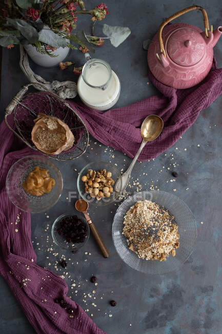 Top view of muesli in glass jar and cup placed on table with nuts and dried berries — Stock Photo