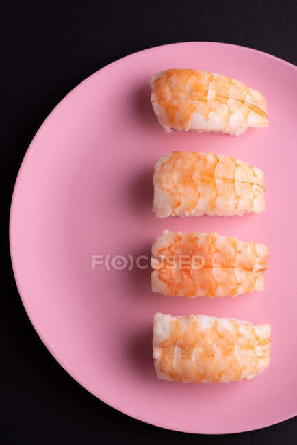 Vista superior del agradable conjunto de sushi Ebi Nigiri servido en el plato sobre fondo oscuro en el estudio - foto de stock