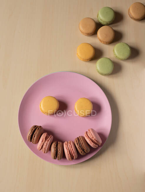 De cima de deliciosos biscoitos de macaron coloridos dispostos em forma de sorriso emoji — Fotografia de Stock