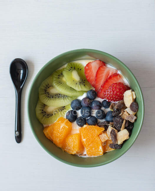 Зверху смачний здоровий сніданок з нарізаними ківі та апельсинами, поміщені в миску з чорницею та полуницею — стокове фото