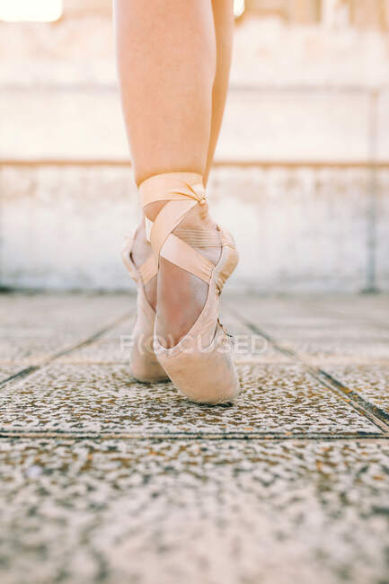 Crop ballerina indossando scarpe a punta in piedi su punte di piedi su terreno di pietra alterato e dimostrando posizione di danza — Foto stock