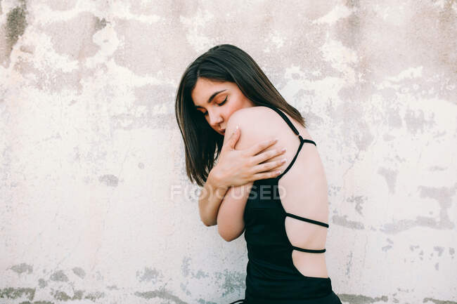 Side view of tranquil female dancer performing with closed eyes on street near stone building in city — Stock Photo
