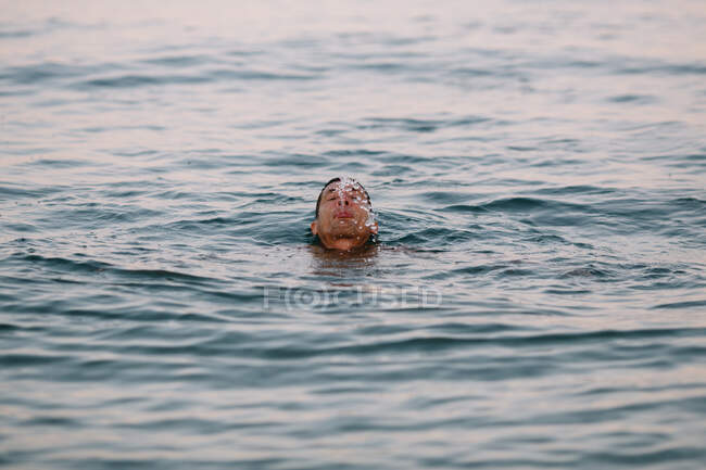 Задоволений чоловік плаває під час здорового активного дозвілля в глибокому спокійному морі, випльовуючи воду після пірнання в сонячний день під час відпустки — стокове фото