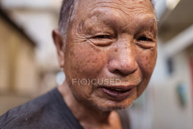 Retrato de idoso asiático jardineiro masculino em roupas casuais sorrindo para a câmera enquanto estava de pé na rua em liquidação em Taiwan — Fotografia de Stock