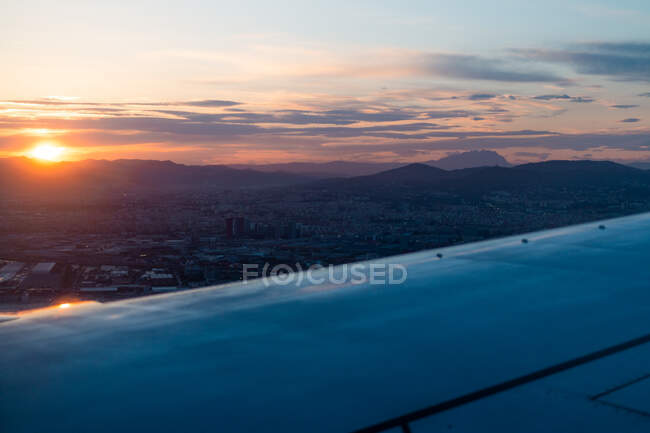 Vista desde la ventana del ala de aviones modernos volando sobre densas nubes durante la puesta del sol - foto de stock