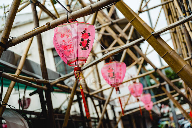 Baixo ângulo de lanternas chinesas rosa ornamentais decorando passarela de bambu, Hong Kong — Fotografia de Stock