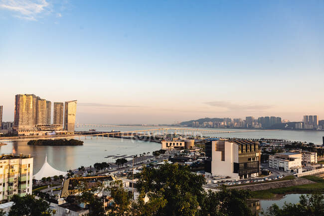 Bâtiments contemporains de grande hauteur et infrastructure de Hong Kong avec vue sur le port sous le soleil couchant — Photo de stock