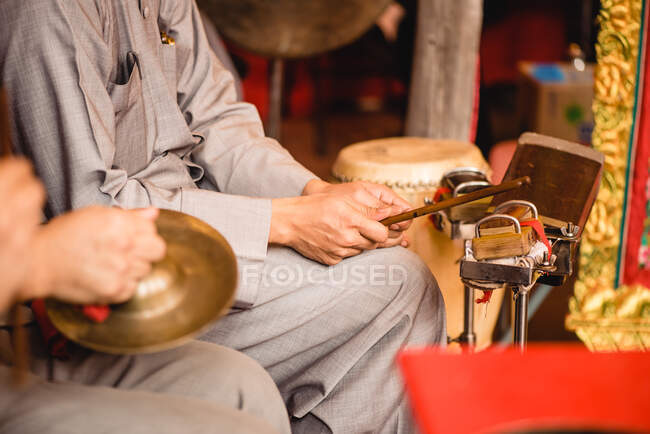 Crop musician playing percussion instruments of traditional Chinese culture in temple of Hong Kong — Stock Photo