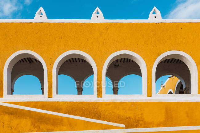 Зовні яскраво-жовті стіни з арками в стародавньому місті Ізамаль проти блакитного неба. — стокове фото