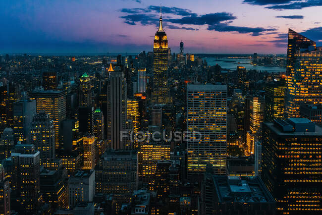 Aerial view of megalopolis with illuminated glass walls and futuristic facades of tall skylines on background of majestic sunset — Stock Photo