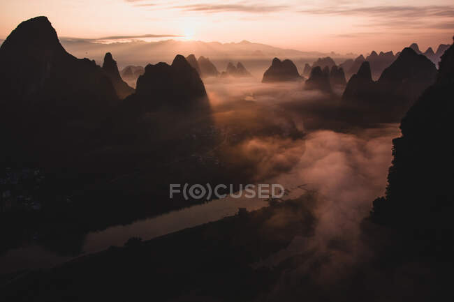 Silhouetten großer hoher Berge gegen strahlend bewölkten Himmel am nebligen Morgen in Guilim — Stockfoto
