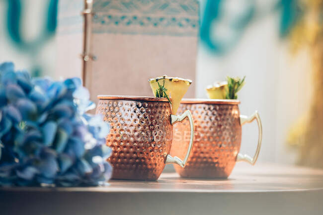 Mugs of cocktail with pineapple pieces and herbs — Stock Photo