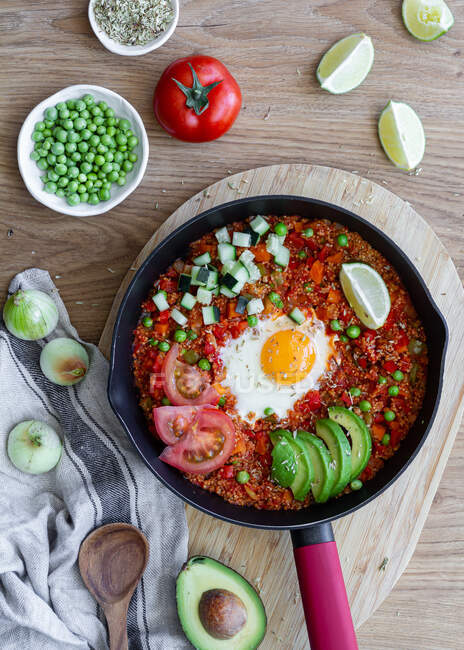 Top view of tasty shakshuka with eggs and quinoa placed on table with fresh ingredients — Stock Photo
