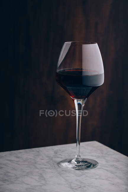 Кришталевий класичний келих червоного вина, розміщений на мармуровому столі на чорному фоні — стокове фото