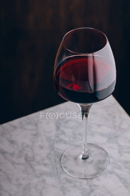 Crystal classic glass of red wine placed on marble table on black background — Stock Photo