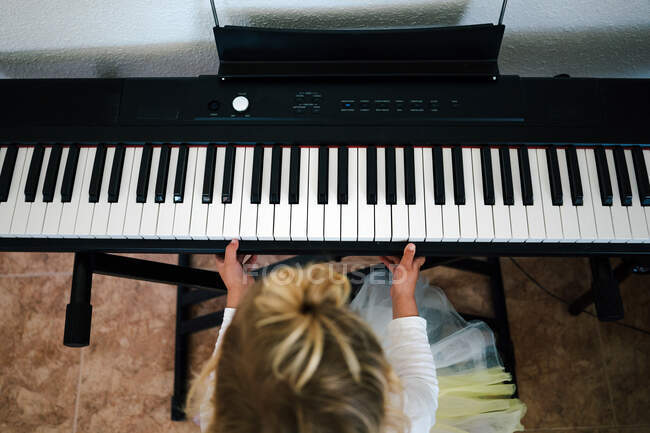 De cima irreconhecível focada menina loira tocando sintetizador em casa — Fotografia de Stock