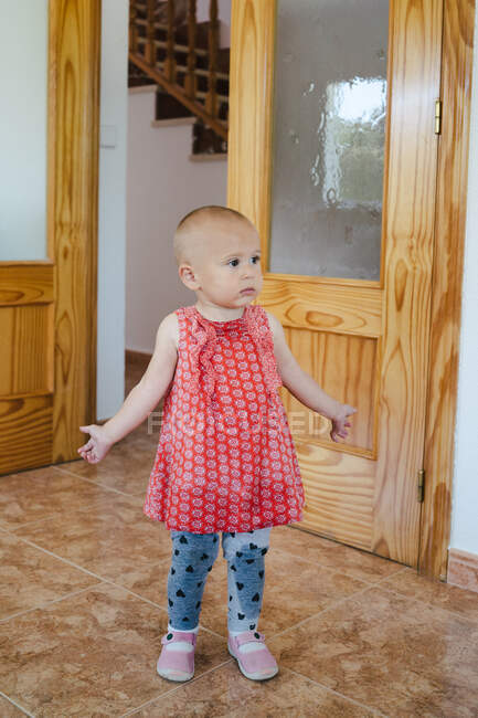Adorable curious girl in wet clothes standing puzzled in middle of room looking around — Stock Photo