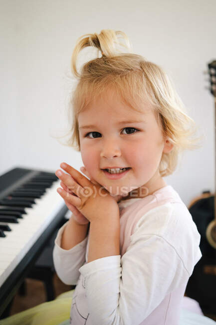 Seitenansicht einer Schülerin im flauschigen Rock, die am Synthesizer sitzt und sich auf den Musikunterricht vorbereitet und in die Kamera schaut — Stockfoto