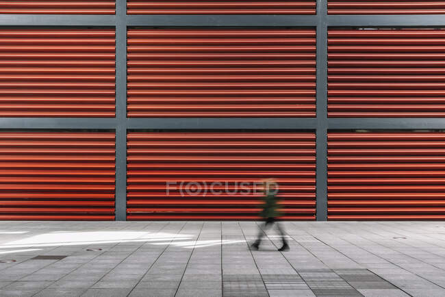 Несконцентрированный человек, идущий к красной стене — стоковое фото