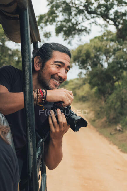 Щасливий подорожуючий чоловік з професійною фотокамерою фотографує дику природу під час сафарі — стокове фото