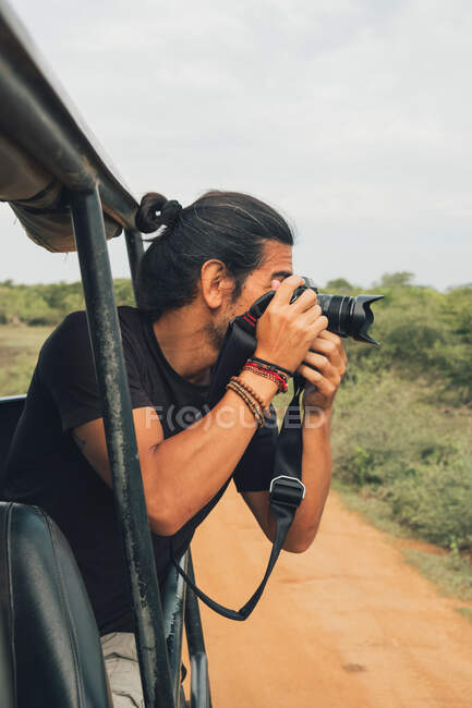 Happy traveling male with professional photo camera taking photos of wildlife during safari — Stock Photo