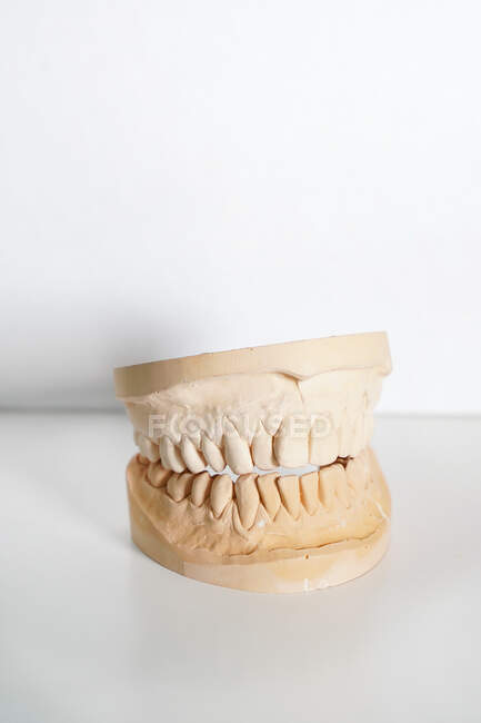 Анонимный стоматолог в медицинских перчатках, держащий протез в современной лаборатории — стоковое фото