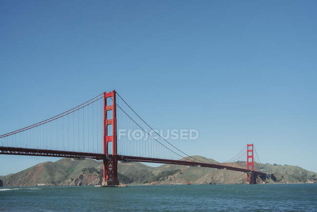 Famosa sospensione Golden Gate Bridge a San Francisco in California con costa collinare e cielo azzurro chiaro sullo sfondo nella giornata di sole — Foto stock