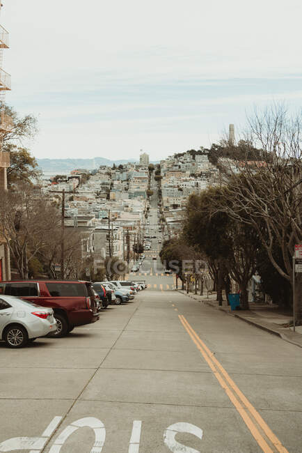 Segnale di stop sulla carreggiata che porta verso visite turistiche con edifici nella città di San Francisco in giornata nuvolosa — Foto stock