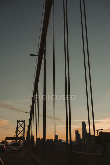 Famous suspension Bay Bridge in San Francisco with moving cars against cloudy sky during sunrise — Stock Photo