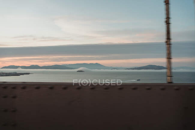 Vue depuis le pont de la baie de San Francisco et de la ville au lever du soleil, avec un ciel nuageux en arrière-plan — Photo de stock
