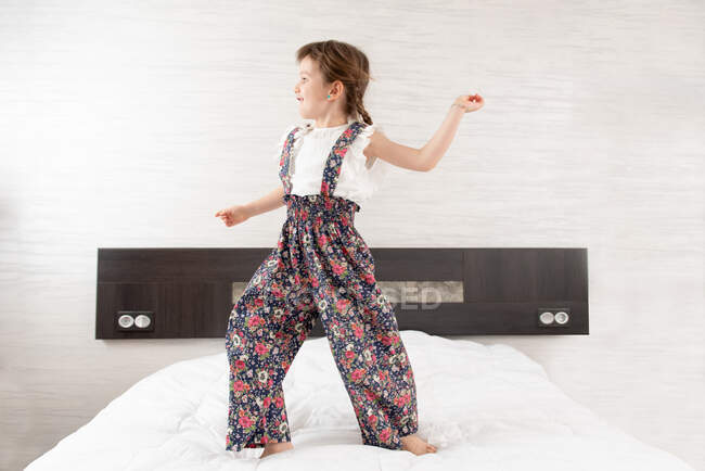 Chica alegre saltando en la cama - foto de stock