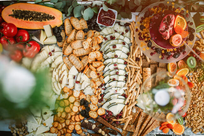 Вид зверху на сир і крекери, поміщені на стіл з випічкою і свіжими фруктами — стокове фото