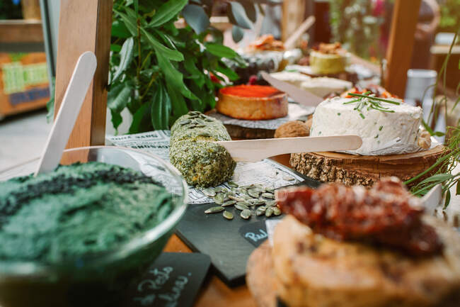 Cottage cheese garnished with greenery and tasty bread with pumpkin seeds placed on wooden table near assorted dishes — Stock Photo