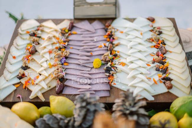 Дерев'яний стіл з різними видами смачного сиру, прикрашений сухофруктами та волоськими горіхами — стокове фото