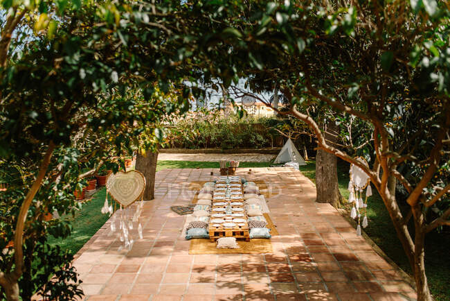 Літня тераса з дерев'яними піддонами у формі столів і затишними подушками, підготовленими для святкування — стокове фото