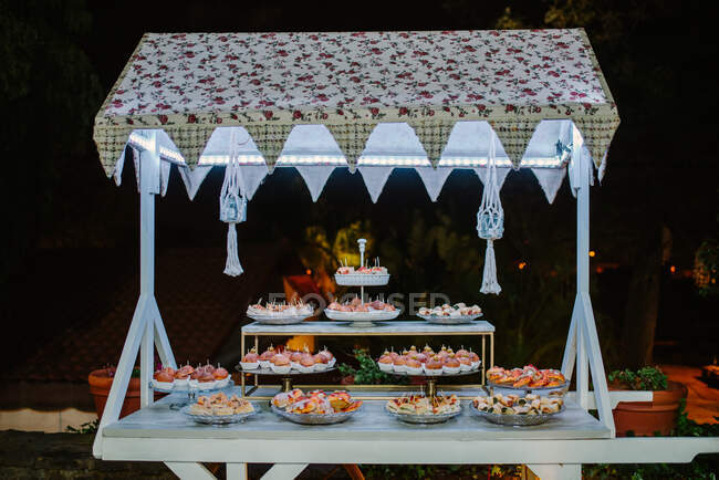 Piatti di gustose tartine poste su bancone illuminato in cortile buio la sera — Foto stock