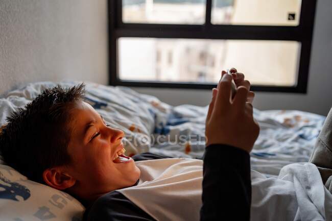 Delighted boy using tablet in bedroom during weekend — Stock Photo