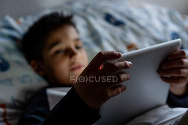 Garoto encantado usando tablet no quarto durante o fim de semana — Fotografia de Stock