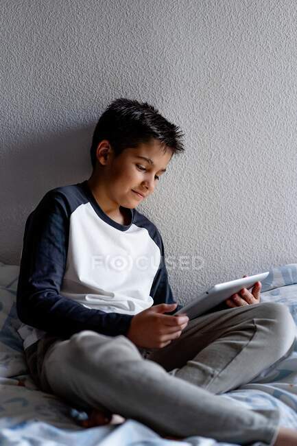 Garoto encantado usando tablet no quarto durante o fim de semana — Fotografia de Stock