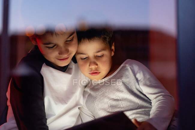 Linda hermanos viendo dibujos animados en la tableta juntos - foto de stock