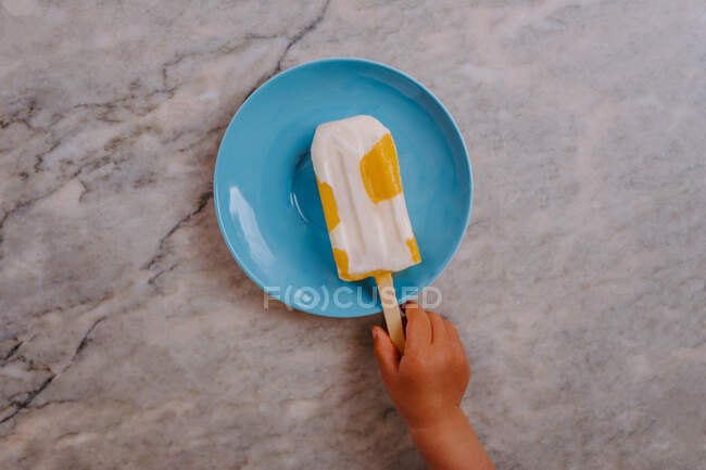 Вид зверху обрізаної непізнаваної руки дитини, що захоплює смачний фруктовий пиріг, розміщений на столі — стокове фото