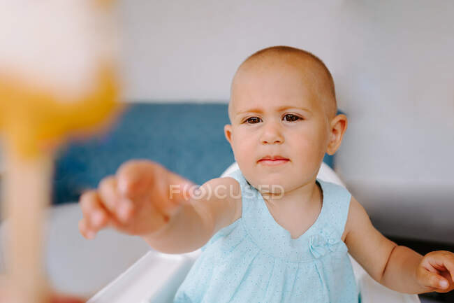Cute toddler sitting on high chair on terrace and eating delicious popsicles while looking away — Stock Photo