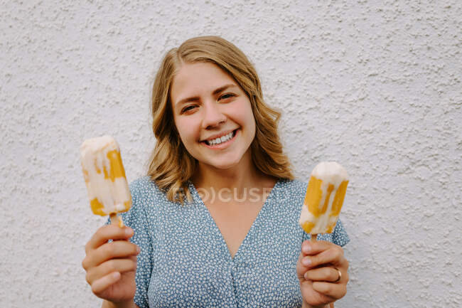 Mulher olhando para a câmera segurando saborosos piruetas de gelo em paus no fundo branco — Fotografia de Stock