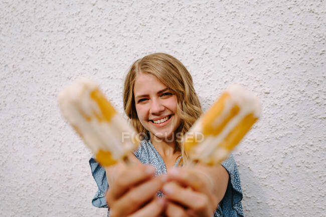 Mujer mirando a la cámara sosteniendo sabrosos chupetes de hielo en palos sobre fondo blanco - foto de stock